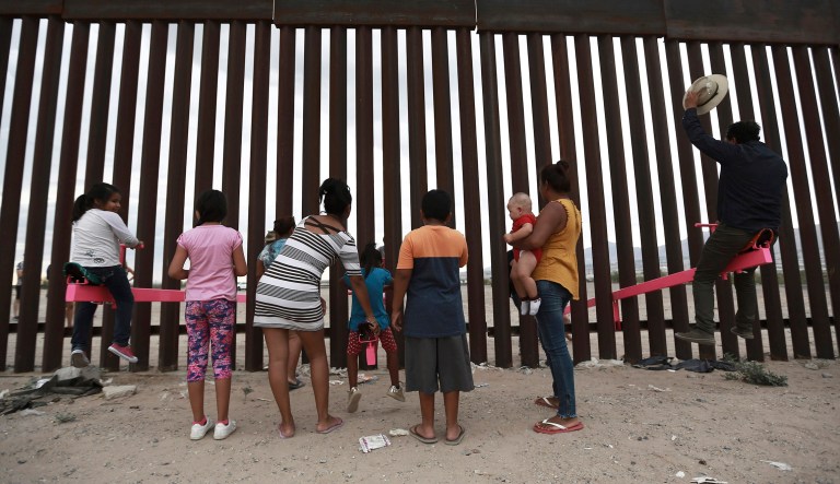 Children and a man play on seesaw installed between the border fence that divides Mexico from the United States in Ciudad de Juarez, Mexico, Sunday, July 28, 2019. The seesaw was designed by Ronald Rael, a professor of architecture in California. 