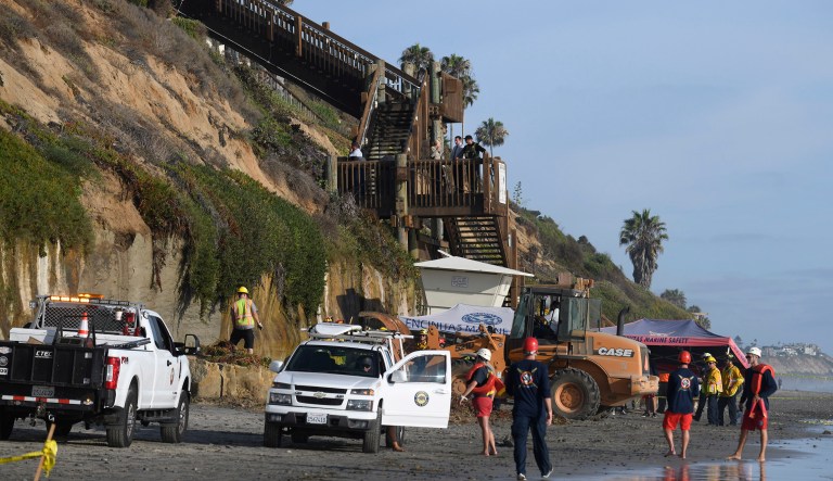 Lifeguards and search and rescue personnel work at the site of a cliff collapse at a popular beach Friday, Aug. 2, 2019, in Encinitas, California.