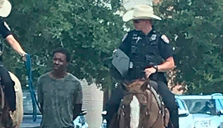 In this photo provided by Erin Toberman, Donald Neely, center, is walked with handcuffs and a rope by two mounted police officers in Galveston, Texas, on Saturday. Galvestonâs police chief has apologized for the way Neely was treated.