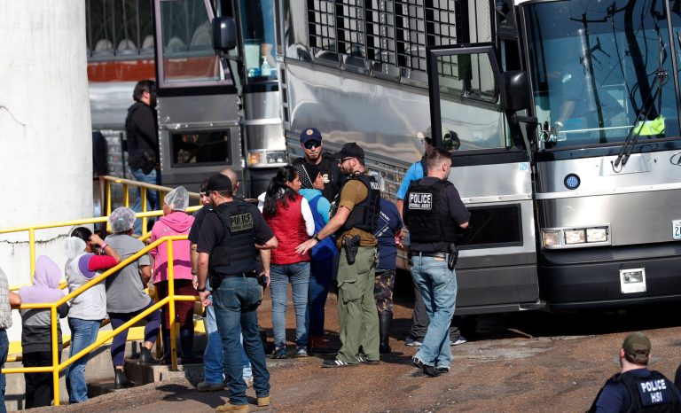 Handcuffed female workers are escorted into a bus for transportation to a processing center following a raid by U.S. immigration officials at a Koch Foods Inc., plant in Morton, Miss., Wednesday, Aug. 7, 2019. 