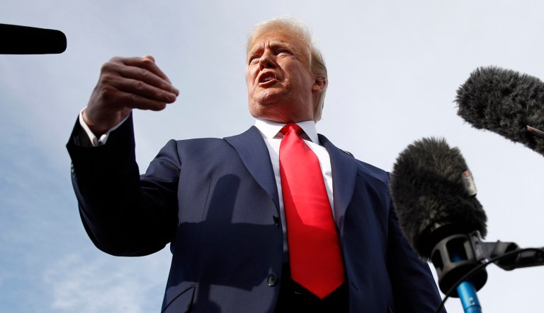 President Trump is surrounded by microphones.