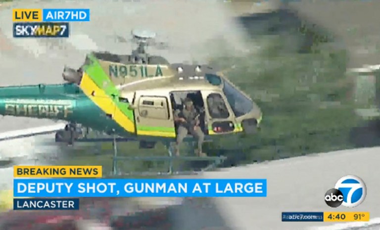 This photo taken from video provided by KABC-TV shows a sheriff's department helicopter with a sniper in an open door searching for a gunman at large in Lancaster, Calif. on Wednesday, Aug. 21, 2019. 