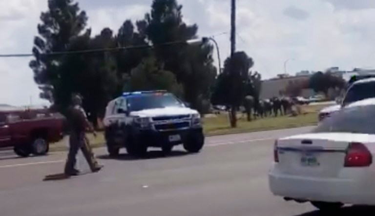 In this image made from video provided by Dustin Fawcett, police officers guard on a street in Odessa, Texas, on Saturday. Police said there are "multiple gunshot victims" in West Texas after reports of gunfire on Saturday in the area of Midland and Odessa.