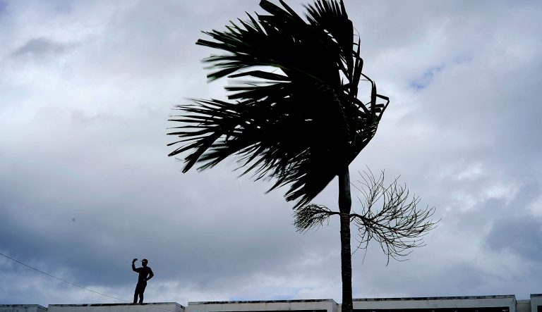 A man stands on a store's roof as he works to prepare it for the arrival of Hurricane Dorian in Freeport on Grand Bahama, Bahamas, Sunday, Sept. 1, 2019. 