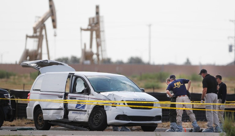 Authorities look at a U.S. Mail vehicle, which was involved in Saturday's shooting, outside the Cinergy entertainment center Sunday in Odessa, Texas.