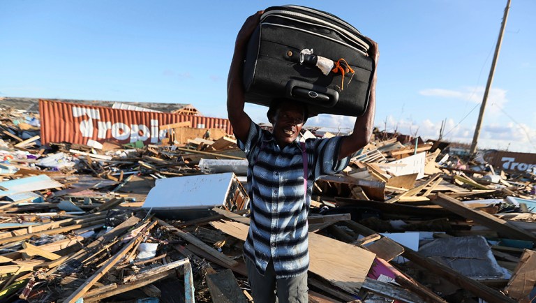 A man carries clothes over what remains of homes in the area called The Mudd after it was devastated by Hurricane Dorian, as he prepares to evacuate Abaco Island, Bahamas, Sunday, Sept. 8, 2019. Dorian was the most powerful hurricane in the northwestern Bahamas' recorded history. (AP Photo/Fernando Llano)