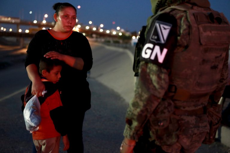 Amilitary police officer wearing the insignia of Mexico's new National Guard detains Guatemalan migrants to keep them from crossing last June from Ciudad Juarez, Mexico to El Paso, Texas.
