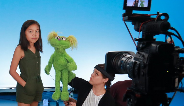 This Aug. 6, 2019 photo shows Salia Woodbury, 10, left, from Irvine, Calif., on the set with "Sesame Street"  muppet Karli and puppeteer Haley Jenkins during a taping about parental addiction in New York. 