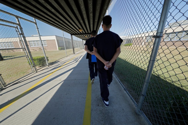 Illegal immigrant detainees walk with their hands clasped behind their backs along a line painted on a walkway inside the Winn Correctional Center in Winnfield, La. in September.