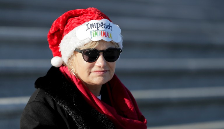 A protester sits on the steps on the House side of the U.S. Capitol building, Wednesday, Dec. 18, 2019, on Capitol Hill in Washington. President Donald Trump is on the cusp of being impeached by the House, with a historic debate set Wednesday on charges that he abused his power and obstructed Congress ahead of votes that will leave a defining mark on his tenure at the White House.