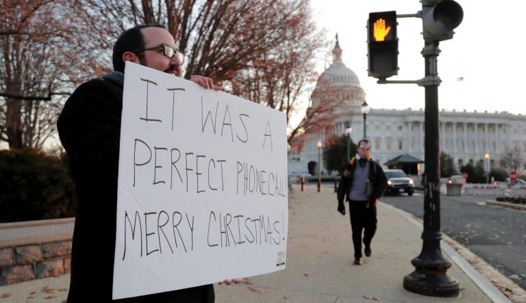 Michael Wille, 33, of Washington, holds a sign at an intersection near the U.S. Capitol, Wednesday, Dec. 18, 2019, on Capitol Hill in Washington. President Donald Trump is on the cusp of being impeached by the House, with a historic debate set Wednesday on charges that he abused his power and obstructed Congress ahead of votes that will leave a defining mark on his tenure at the White House.