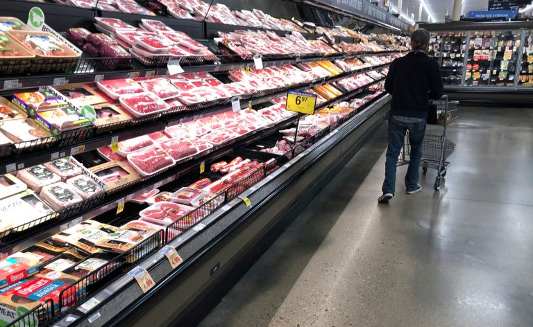 A shopper pushes his cart past a display of packaged meat in a grocery store Sunday, May 10, 2020, in southeast Denver.