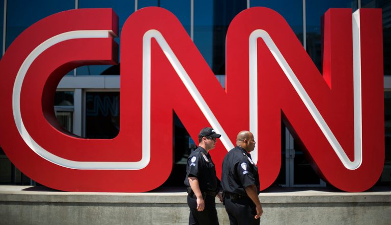 In this Aug. 26, 2014 photo, security guards walk past the entrance to CNN headquarters in Atlanta. 