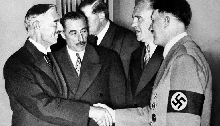 Hands clasped in friendship, Adolf Hitler and England's Prime Minister Neville Chamberlain, are shown in this historic pose at Munich on Sept. 30, 1938.   This was the day when the premier of France and England signed the Munich agreement, sealing the fate of Czechoslovakia.   Next to Chamberlain is Sir Neville Henderson, British Ambassador to Germany.   Paul Schmidt, an interpreter, stands next to Hitler.