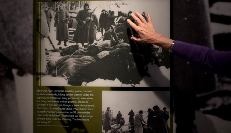 U.S. Holocaust Memorial Museum curator points out a 1942 photo of Ukrainian auxiliary police killing Jewish women under the supervision of German army personnel and in the presence of Hungarian troops.