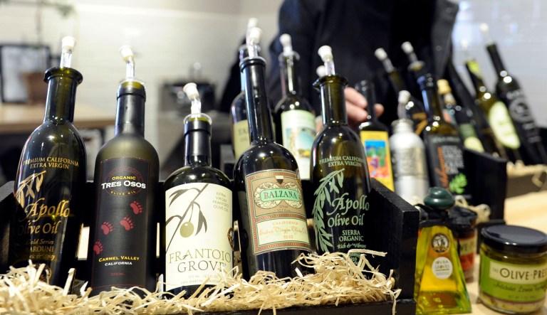 This photo taken Feb. 12, 2014 shows California Olive Oil Council Executive Director Patricia Darragh posing with a collection of California olive oil at the All Things Olive shop in Washington. It's a pressing matter for the tiny U.S olive oil industry. Shoppers are more often pouring European oil _ it's cheaper and viewed as more authentic than the American competition. And that's pitting U.S. producers against importers of the European oil. Some liken the battle to the California wine industry's struggles to gain acceptance decades ago. The tiny California olive industry says European olive oil filling U.S. shelves often is mislabeled and lower grade. They're pushing the federal government to give more scrutiny to imported varieties. One congressman-farmer even goes as far as suggesting labels on imported oil say "extra rancid" rather than extra virgin. Stricter standards might help American producers grab more market share from the dominant Europeans. 