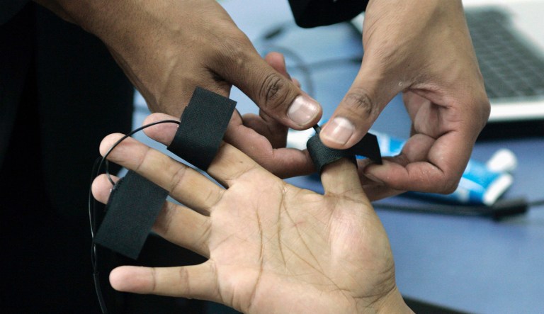 In this June 12, 2007, file photo, a polygraph examiner applies electrodes on the fingers of a subject in Bogota, Colombia. Scientists say we all lie, and this year, politicians are bending the truth big time, with real consequences. By studying how and why we deceive, the experts say they can help us better understand the 2016 election season.