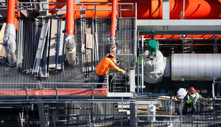 Employees work next to the gas lines of the Mississippi Power Co. carbon capture power plant in DeKalb, Mississippi.