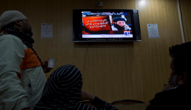 People watch a news report on TV about leader of Pakistani Taliban leader Mullah Fazlullah in Islamabad, Pakistan. 