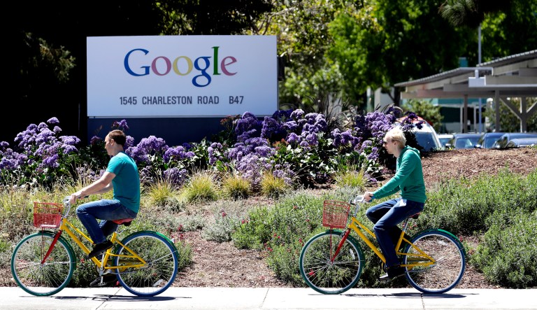 Cyclists ride past a Google sign at the company's headquarters in Mountain View, Calif.