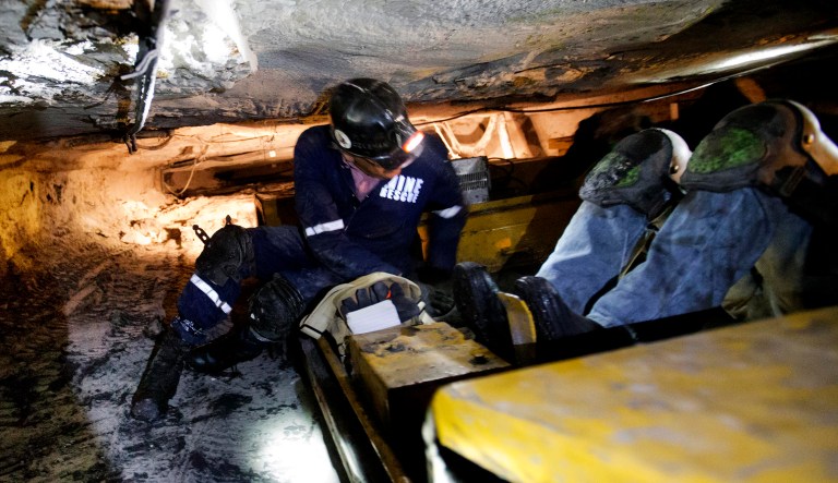 Donnie Coleman, chief safety director and a coal miner of nearly 40 years, crawls into a buggy that transports miners while laying down through a coal mine roughly 40-inches-high, in Welch, W.Va.