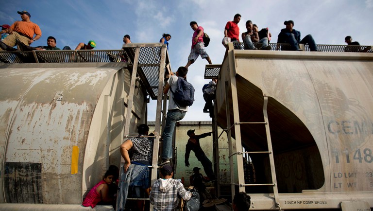 Central American migrants climb on a north bound train during their journey toward the U.S.-Mexico border.