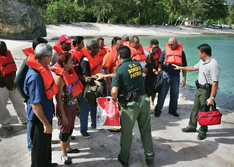 En route to processing on mainland Puerto Rico, U.S. Border Patrol agents help Cuban immigrants put on life vests as they prepare to depart Puerto Rico's remote Mona Island, a nature preserve roughly halfway between the Dominican Republic and Puerto Rico, and where the Cubans had arrived by boat earlier, June 13, 2006. Taking the back door into the United States, droves of Cubans are heading to Puerto Rico instead of north to mainland U.S., crossing some of the world's stormiest seas to this small an island belonging to Puerto Rico, a U.S. Territory. 