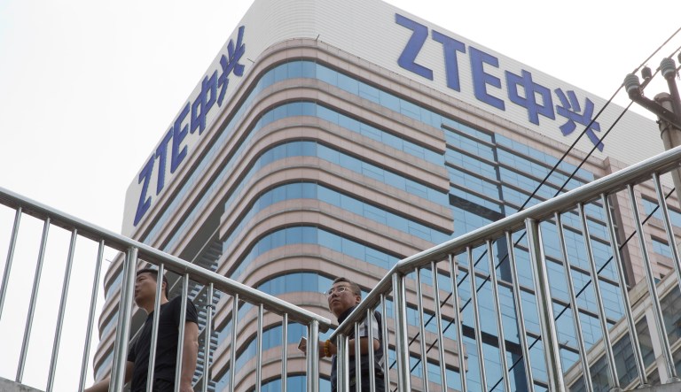 In this May 8, 2018, file photo, Chinese men pass by a ZTE building in Beijing, China.