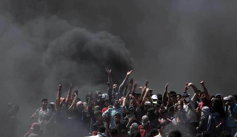 Palestinian protesters chant slogans as they burn tires during a protest on the Gaza Strip's border with Israel. Thousands of Palestinians are protesting near Gaza's border with Israel, as Israel prepared for the festive inauguration of a new U.S. Embassy in contested Jerusalem. 