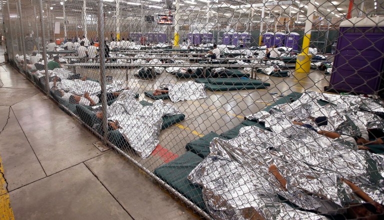 In this June 18, 2014, file photo, detainees sleep and watch television in a holding cell where hundreds of mostly Central American immigrant children are being processed and held at the U.S. Customs and Border Protection Nogales Placement Center in Nogales, Arizona.