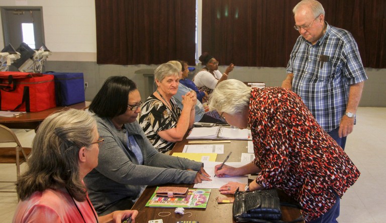 Poll workers assist voters as they sign in to vote Tuesday morning in Hickory, Miss. 