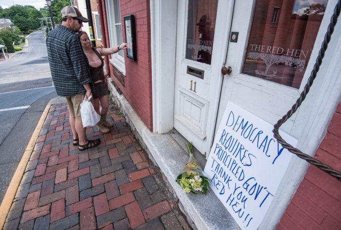 Passersby examine the menu at the Red Hen Restaurant Saturday, June 23, 2018, in Lexington, Va. Former White House press secretary Sarah Huckabee Sanders was booted from the Virginia restaurant because the owner didn't like her former boss, President Donald Trump.