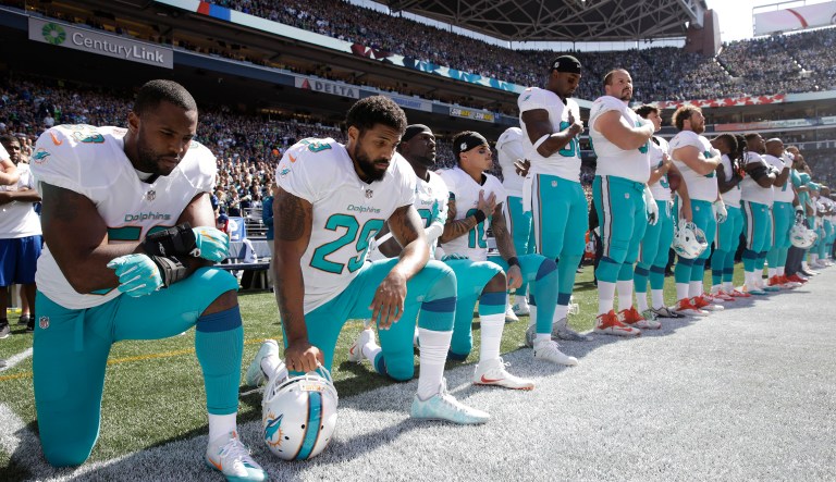 Miami Dolphins' Jelani Jenkins, Arian Foster, Michael Thomas, and Kenny Stills, kneel during the singing of the national anthem before an NFL football game. 