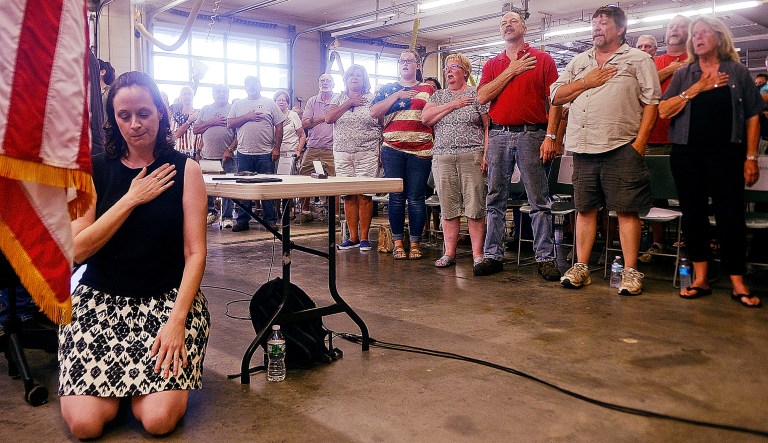 Selectwoman Melissa Schlag kneels for the Pledge of Allegiance during a Haddam, Conn., board of selectmen meeting on Monday at the Haddam firehouse. 