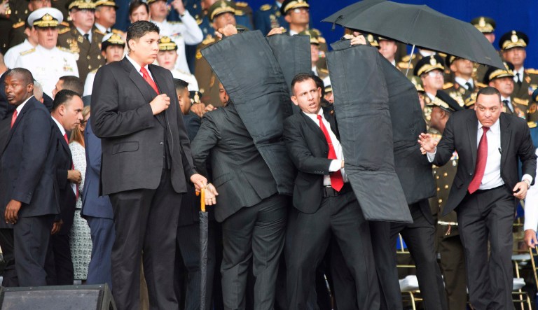 Security personnel surround Venezuela's President Nicolas Maduro as drones armed with explosives detonated near him, but the socialist leader was unharmed, according to the government.