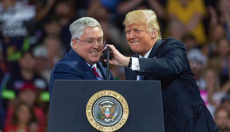 President Trump adjusts the microphone for West Virginia Attorney General Patrick Morrisey during a rally.  