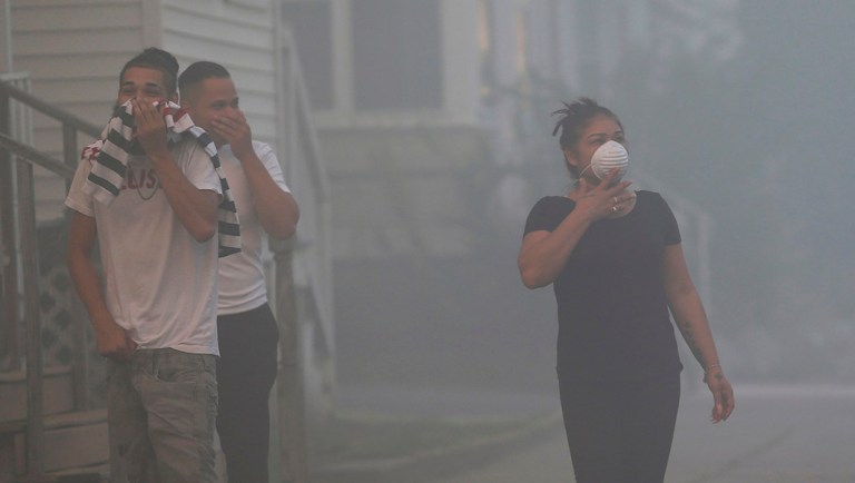 People cover their faces to protect themselves from heavy smoke from a fire on Bowdoin Street in Lawrence, Mass.