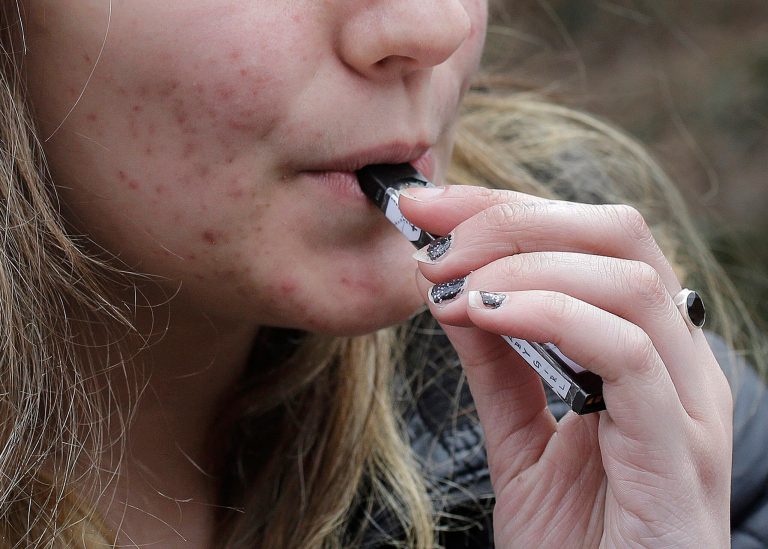 FILE - In this April 11, 2018, file photo, a high school student uses a vaping device near a school campus in Cambridge, Mass. (AP Photo/Steven Senne, File)