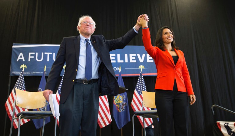 In this April 22, 2016 file photo, former Democratic presidential candidate Sen. Bernie Sanders, I-Vt., holds hands with Rep. Tulsi Gabbard, D-Hawaii, during a town hall at Gettysburg College, in Gettysburg, Pa. 