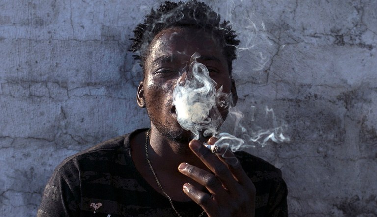 FILE - In this Tuesday, Sept. 18, 2018, file photo, a Malawian migrant Jonas smokes marijuana on the rooftop of an abandoned building in downtown Johannesburg. 2018 has been called the "year for cannabis" in South Africa. But there are still hurdles before a legal marijuana industry can flourish in an African economic power deemed ideal for large-scale cultivation.