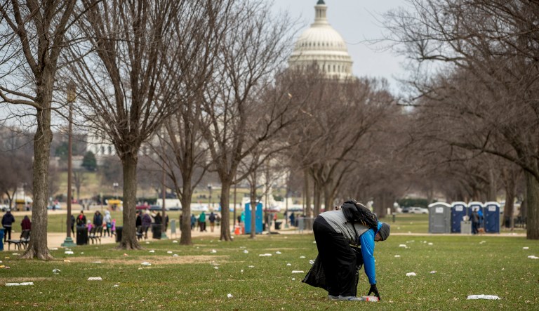 In this Dec. 25, 2018, file photo, the Capitol building is visible as a man picks up garbage during a partial government shutdown on the National Mall in Washington. No city experiences a shutdown quite like Washington. Besides the economic impact, a shutdown warps the nationâs capital on a cultural, recreational, and logistical level. 