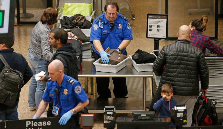 A TSA worker helps passengers at the Salt Lake City International Airport, Wednesday, Jan. 16, 2019, in Salt Lake City. The government shutdown has generated an outpouring of generosity to TSA agents and other federal employees who are working without pay. In Salt Lake City, airport officials treated workers from the TSA, FAA and Customs and Border Protection to a free barbecue lunch as a gesture to keep their spirits up during a difficult time.