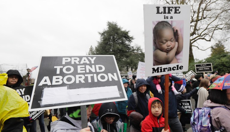 People taking part in an anti-abortion march and rally hold signs as the walk toward the Legislative building, Tuesday, Jan. 22, 2019, at the Capitol in Olympia, Wash. The event was part of annual 