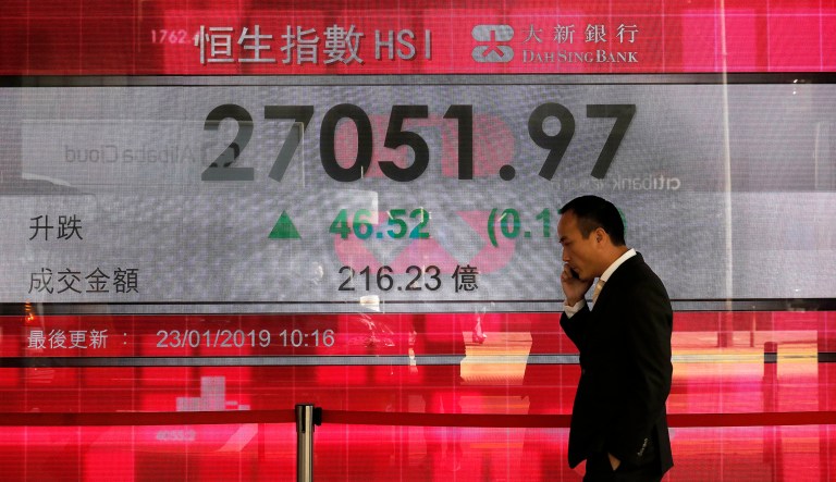 A man walks past an electronic board showing Hong Kong share index outside a local bank in Hong Kong, Wednesday, Jan 23, 2019. Asian markets edged higher on Wednesday but trading was subdued with poor Japanese trade data and a possible bump in U.S-China talks.