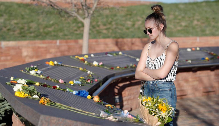 Sixteen-year-old Maren Strother of Denver looks over the plaques for the victims of the Columbine High School massacre before a vigil at the memorial for the victims of the attack nearly 20 years ago Friday, April 19, 2019, in Littleton, Colo.