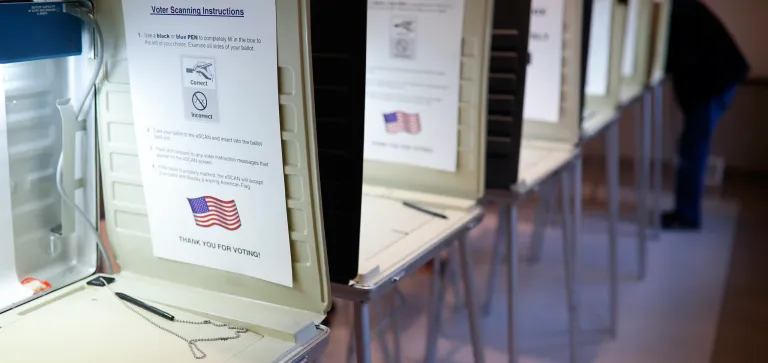 FILE- In this Nov. 8, 2016, file photo a lone voter fills out a ballot alongside a row of empty booths at a polling station in the Terrace Park Community Building on Election Day in Cincinnati. (AP Photo/John Minchillo, File)