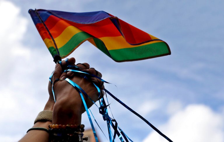 A gay couple holds hands, clutching a rainbow flag, during the gay pride parade in Bogota, Colombia, Sunday, June 30, 2019. Thousands paraded during the annual gay pride parade in support of peace and against sexual discrimination.
