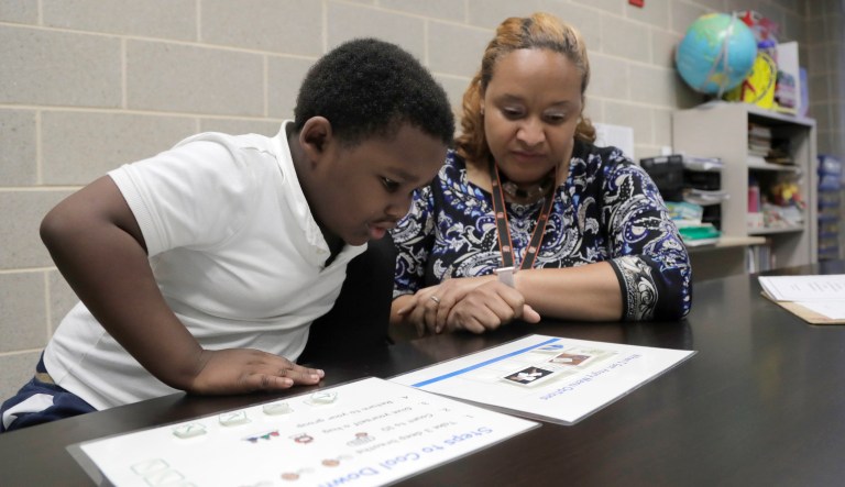 In a photo taken Tuesday, July 2, 2019, New Song Community Learning Center principal Lisa Brown, right, works with Eli Stratton, 5, a kindergarten student, with a stress diminishing exercise at the West Baltimore school.