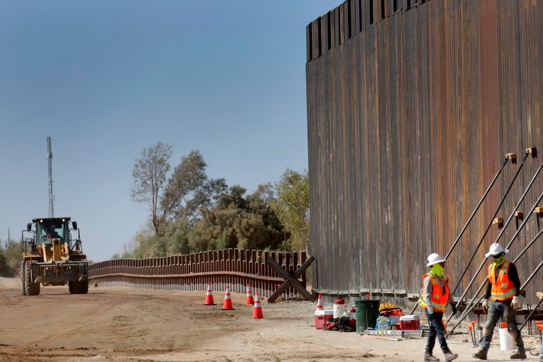 Government contractors erect a section of border wall along the Colorado River, in Yuma, Ariz., in September.