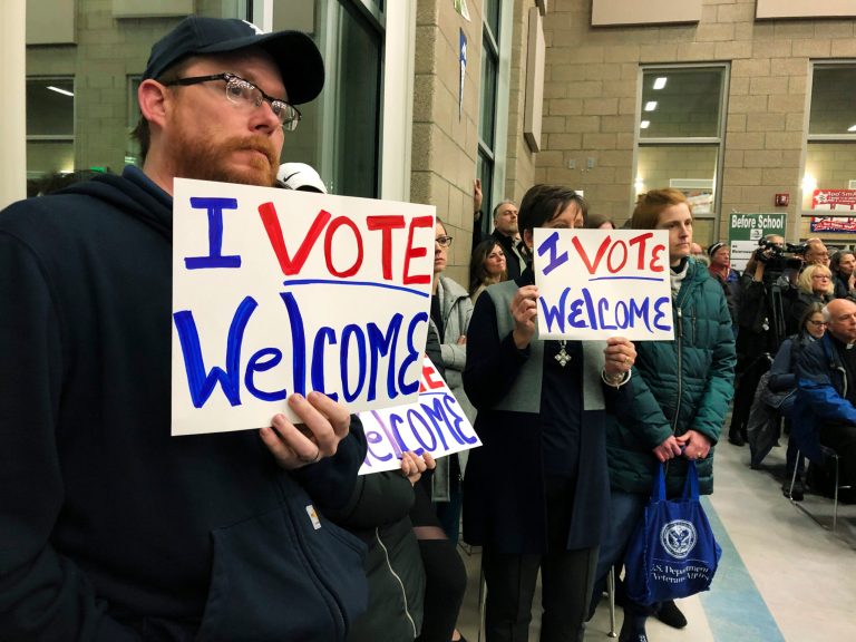 Residents in support of continued refugee resettlement hold signs at a meeting in Bismarck, N.D.